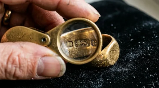 Close-up view of examining British hallmarks on a gold ring with a jeweller's loupe