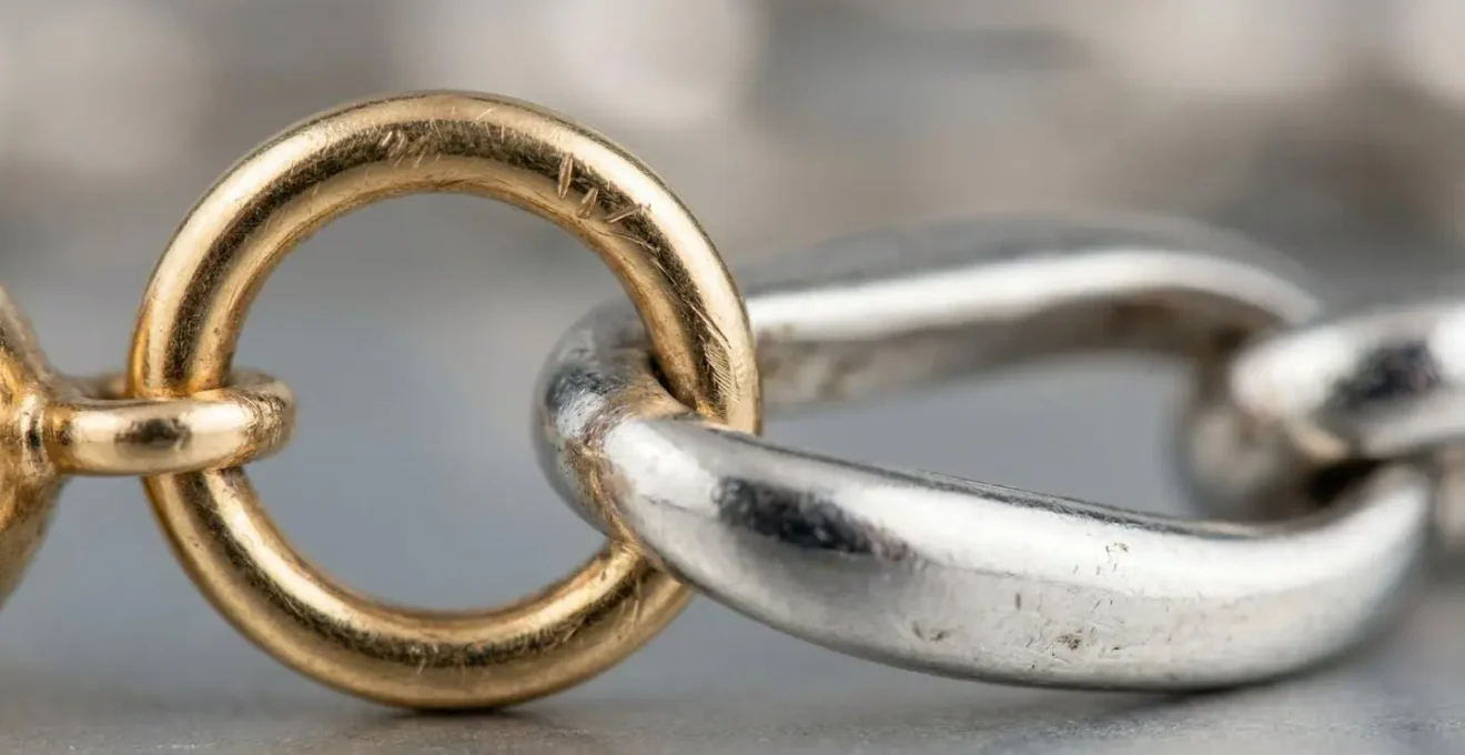 Microscopic view of gold charm attachment point on platinum bracelet showing wear patterns