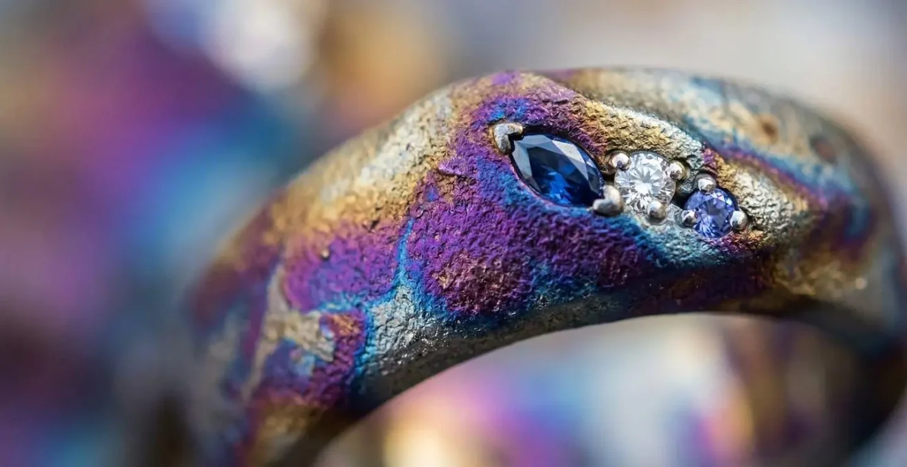 Macro photography of titanium jewelry surface showing iridescent colors and innovative setting techniques